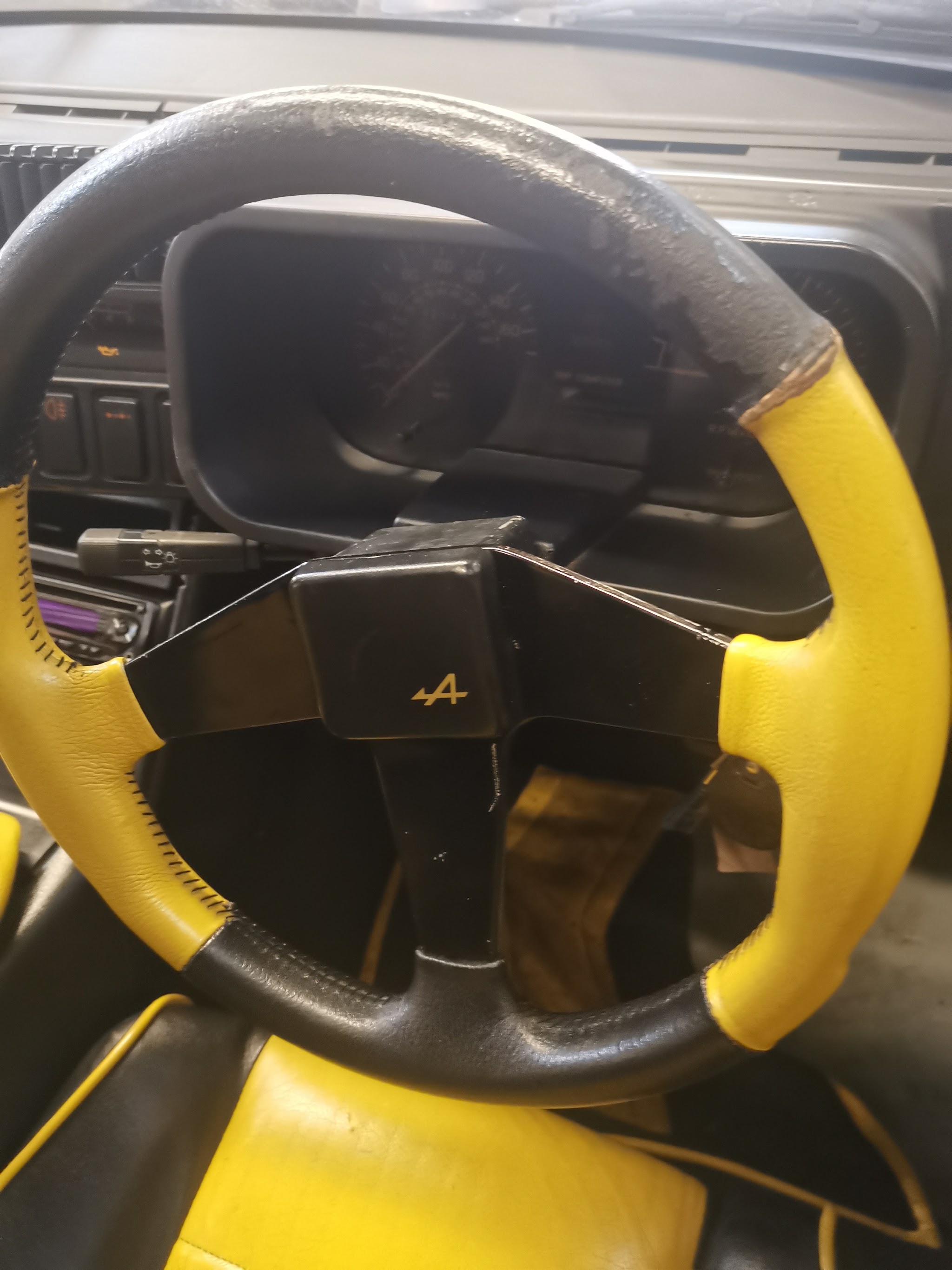 Close-up of a yellow and black leather steering wheel in a car at the garage